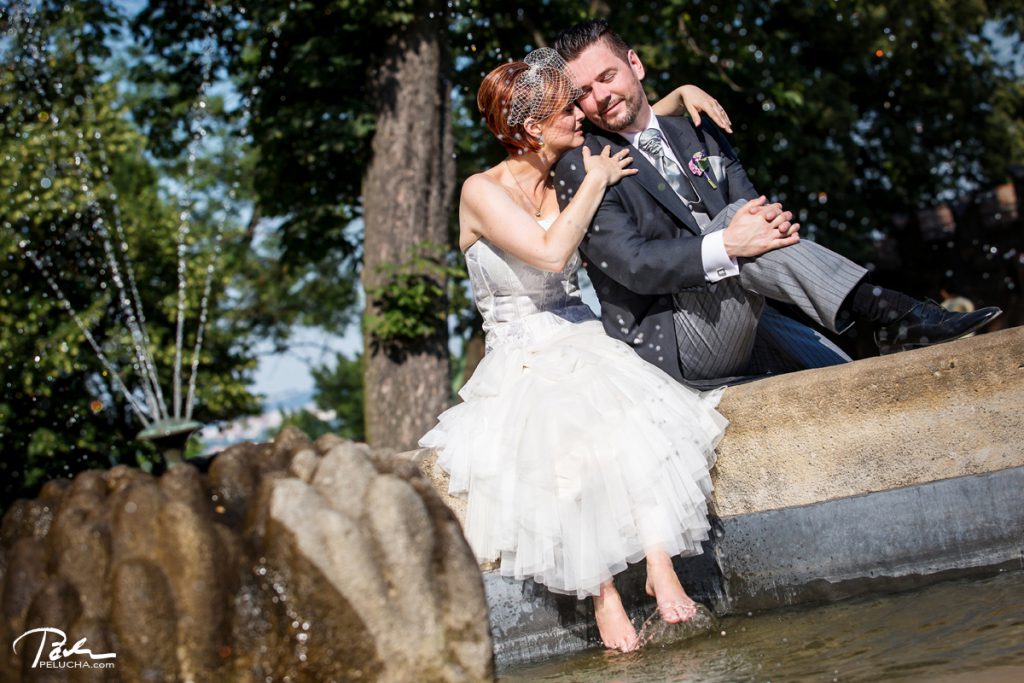 bride and groom sitting by the founting with her feet soaked in water